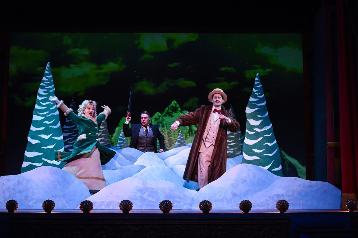 Man and Woman singing on stage with a snow covered backdrop.