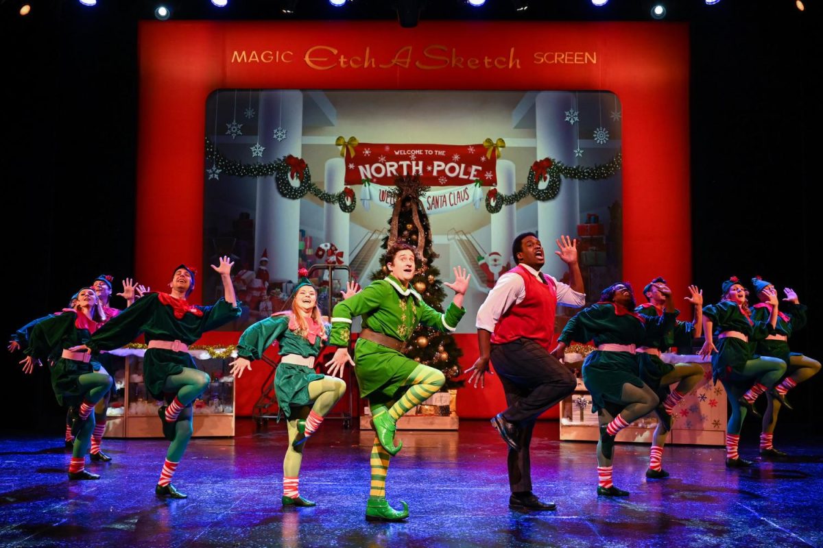 Cast dressed as Christmas Elves dancing on stage.