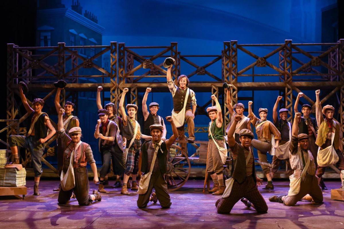 Cast on stage wearing newsboy caps.