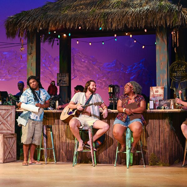 3 people singing on bar stools in front of a tiki bar.