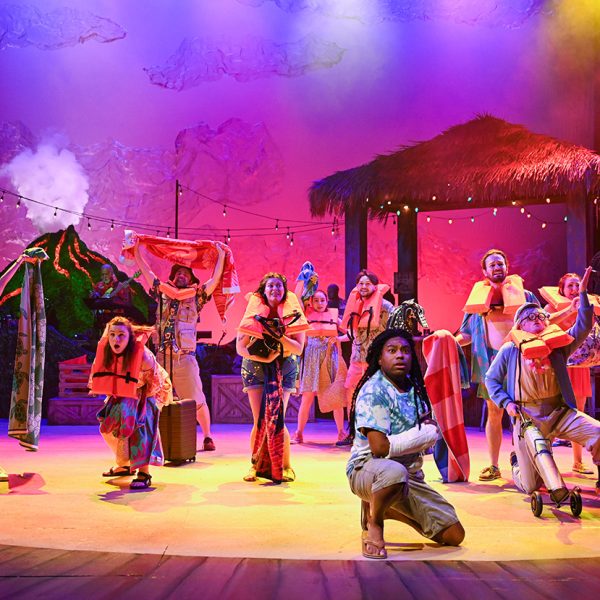 Men and women wearing life jackets on stage in front of a tiki bar.